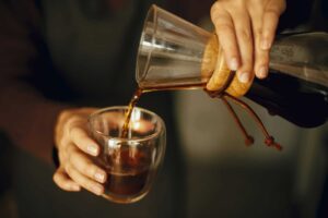 Professional female barista in black uniform making drip coffee
